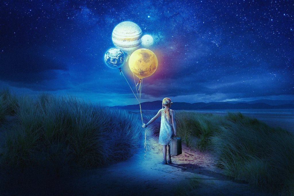 Person an Strand mit leuchtenden Planeten an Schnüren vor Sternenhimmel und Wasser