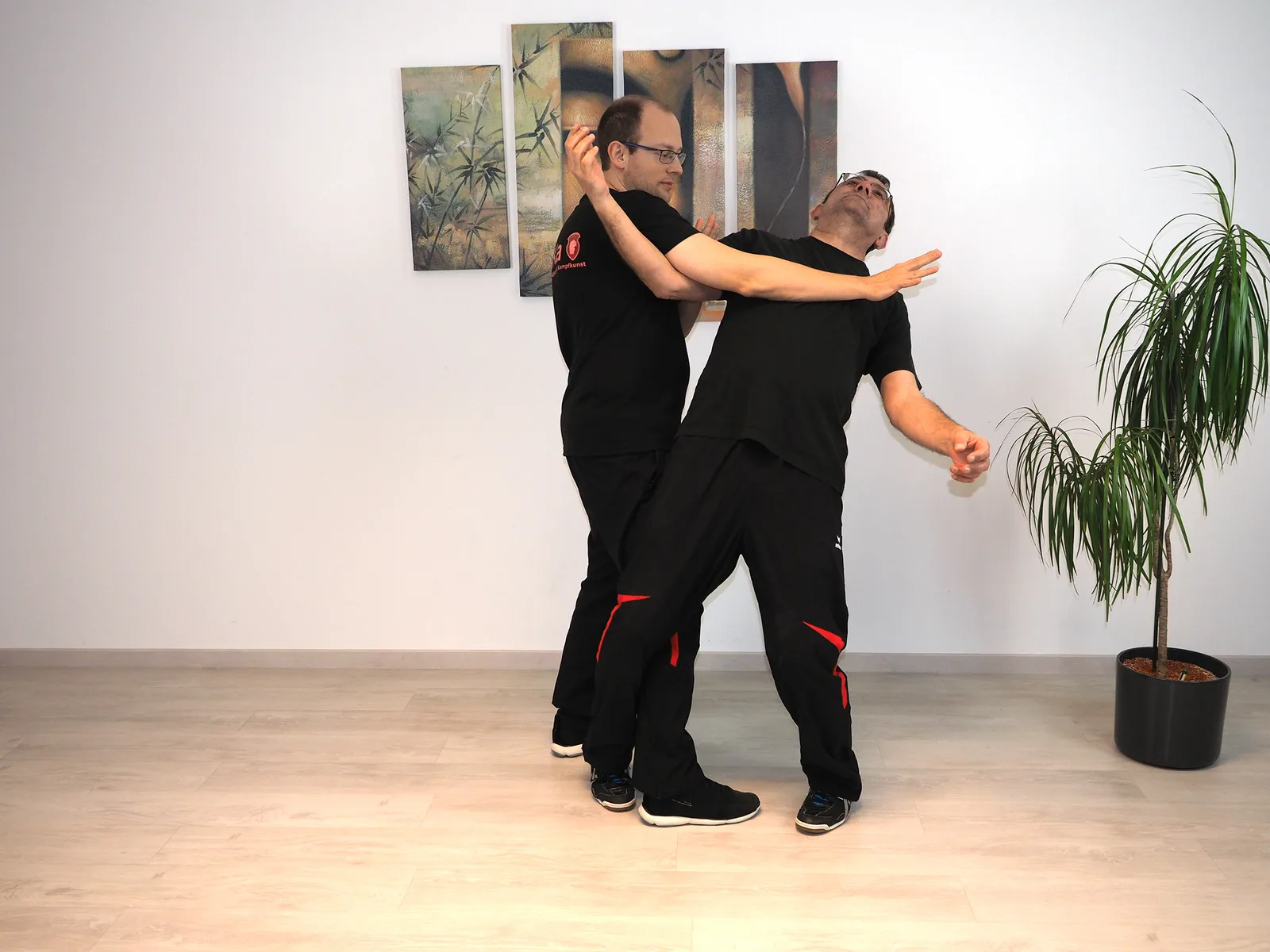 Instruktor demonstriert Panantukan-Handkampftechniken gegen Partner mit ausgestrecktem Arm