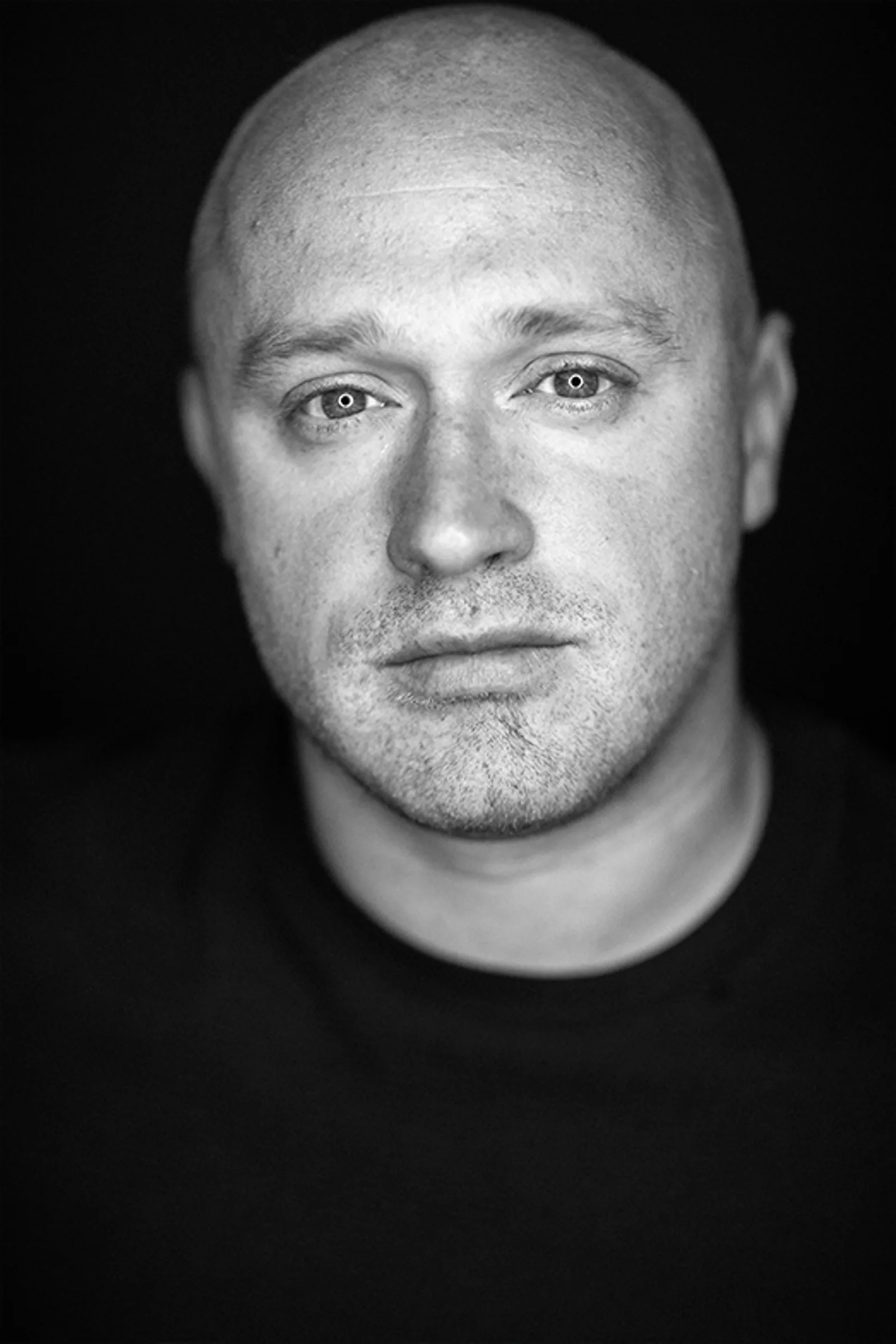 Schwarz-Weiß Porträt von Danny Adams, Autor des Disziplin-Masterkurs, frontal vor dunklem Hintergrund