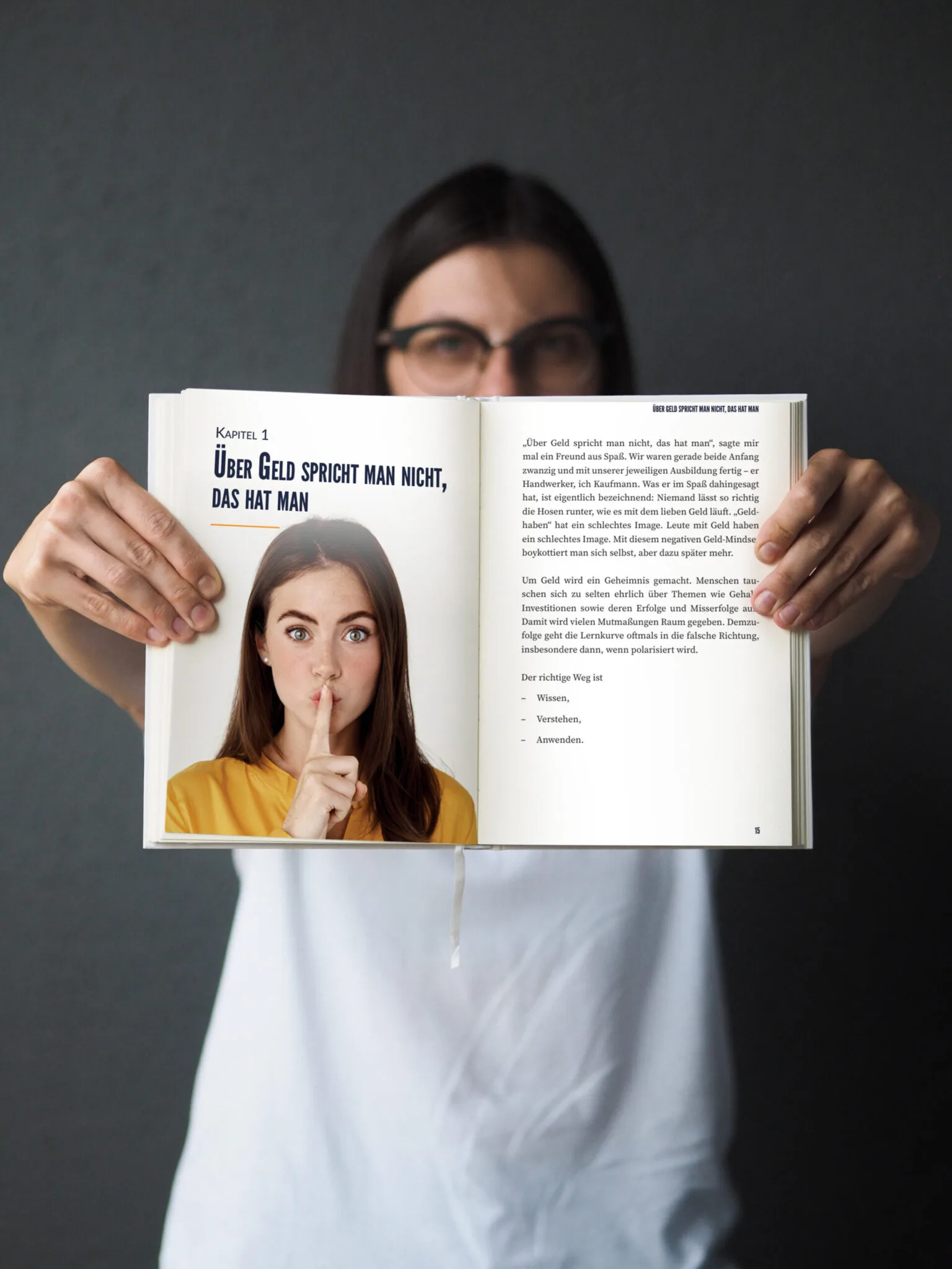 Frau in weißem Oberteil hält aufgeschlagenes Buch, zeigt Seite mit Kapitel 1 und Frauenporträt in gelbem Pullover