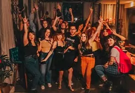 Gruppe junger Menschen feiert ausgelassen auf Party mit Musik und Lichtern