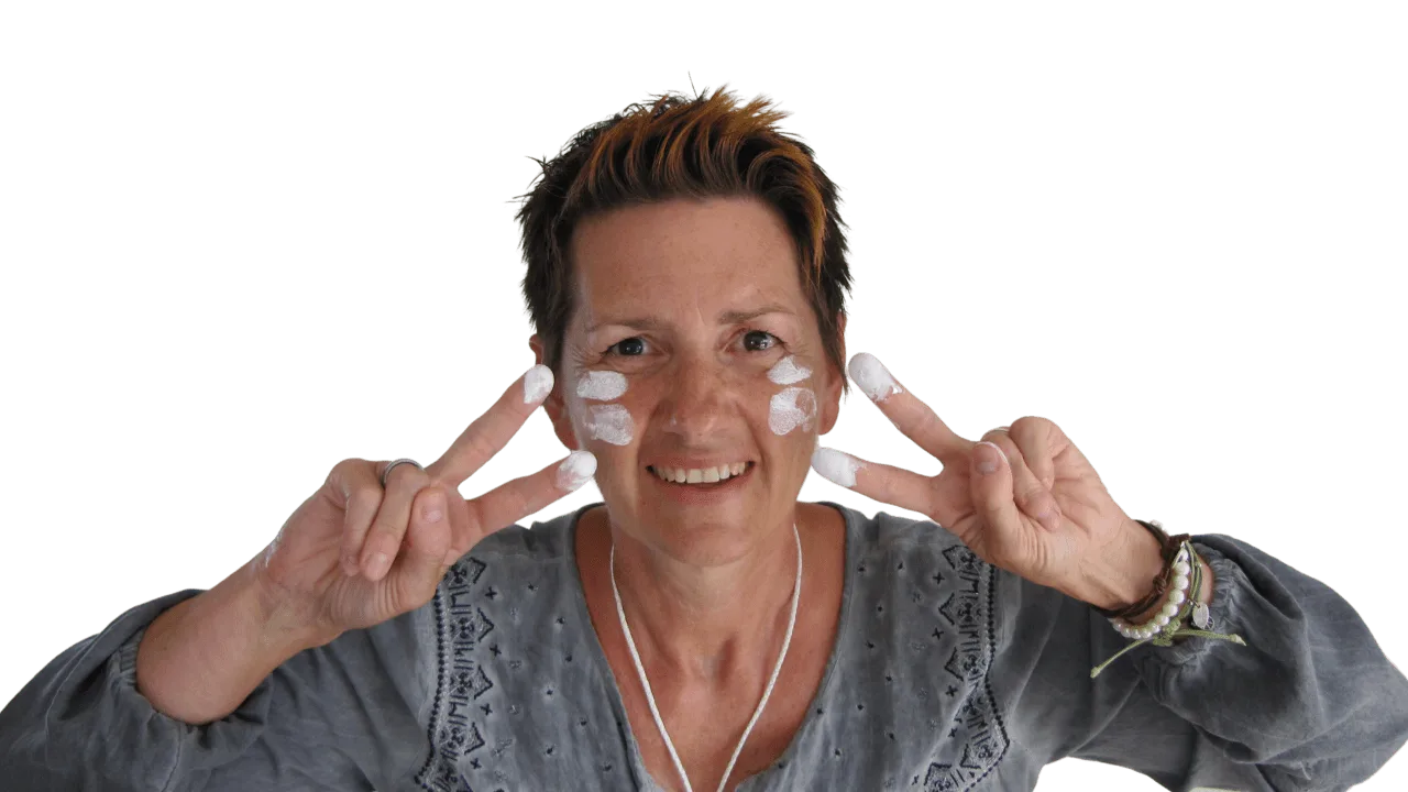 Andrea Kutsch mit weißen Anstrichproben auf den Wangen, lächelnd, graues Shirt mit Print