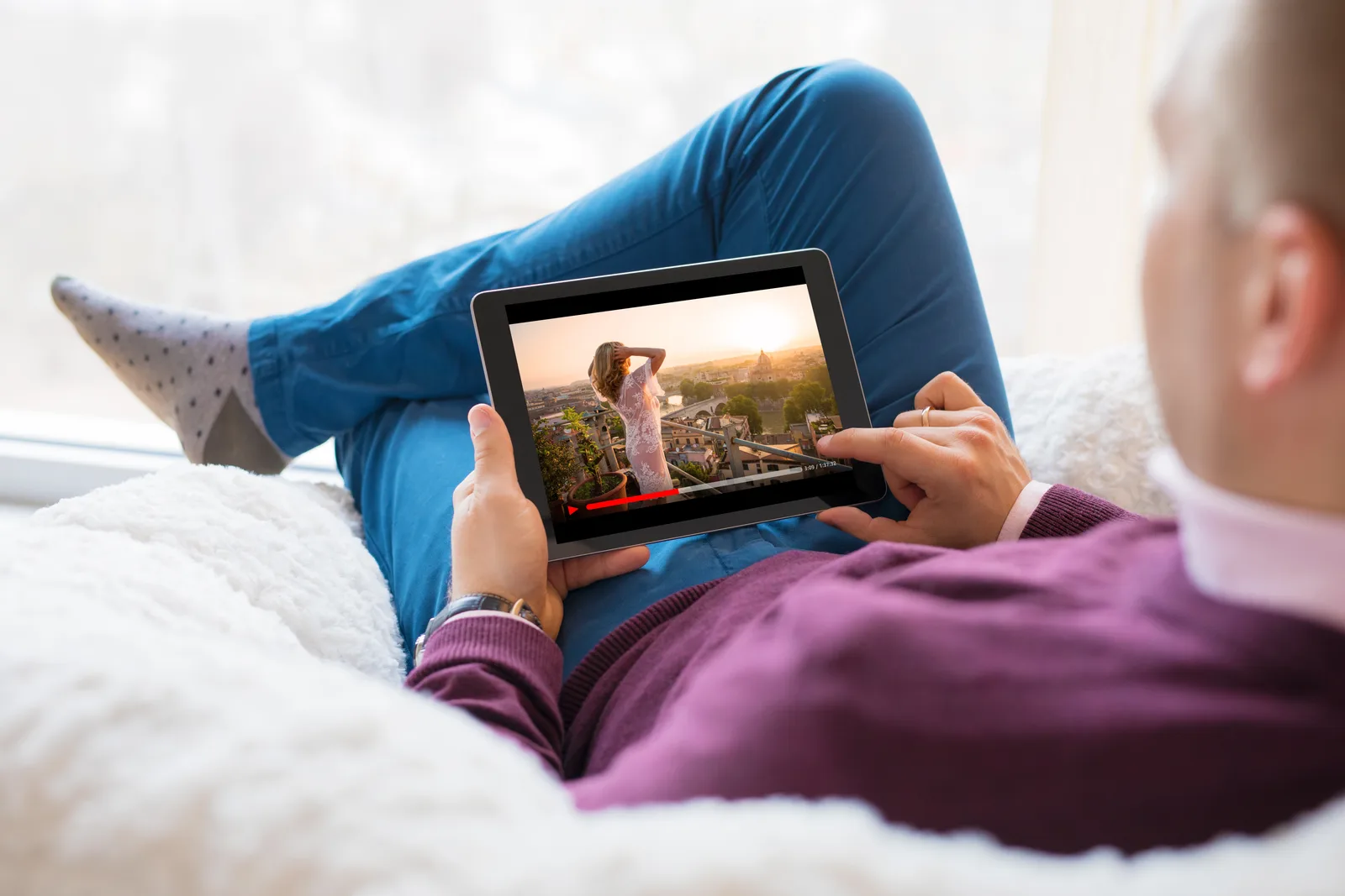 Person hält Tablet mit Video von Reisescene, entspannte Pose