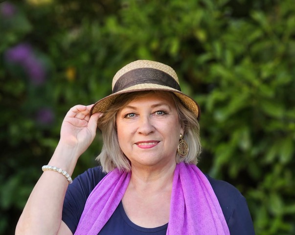 Marina Thomsen Portrait, Frau mit Hut und lila Schal vor grünem Hintergrund