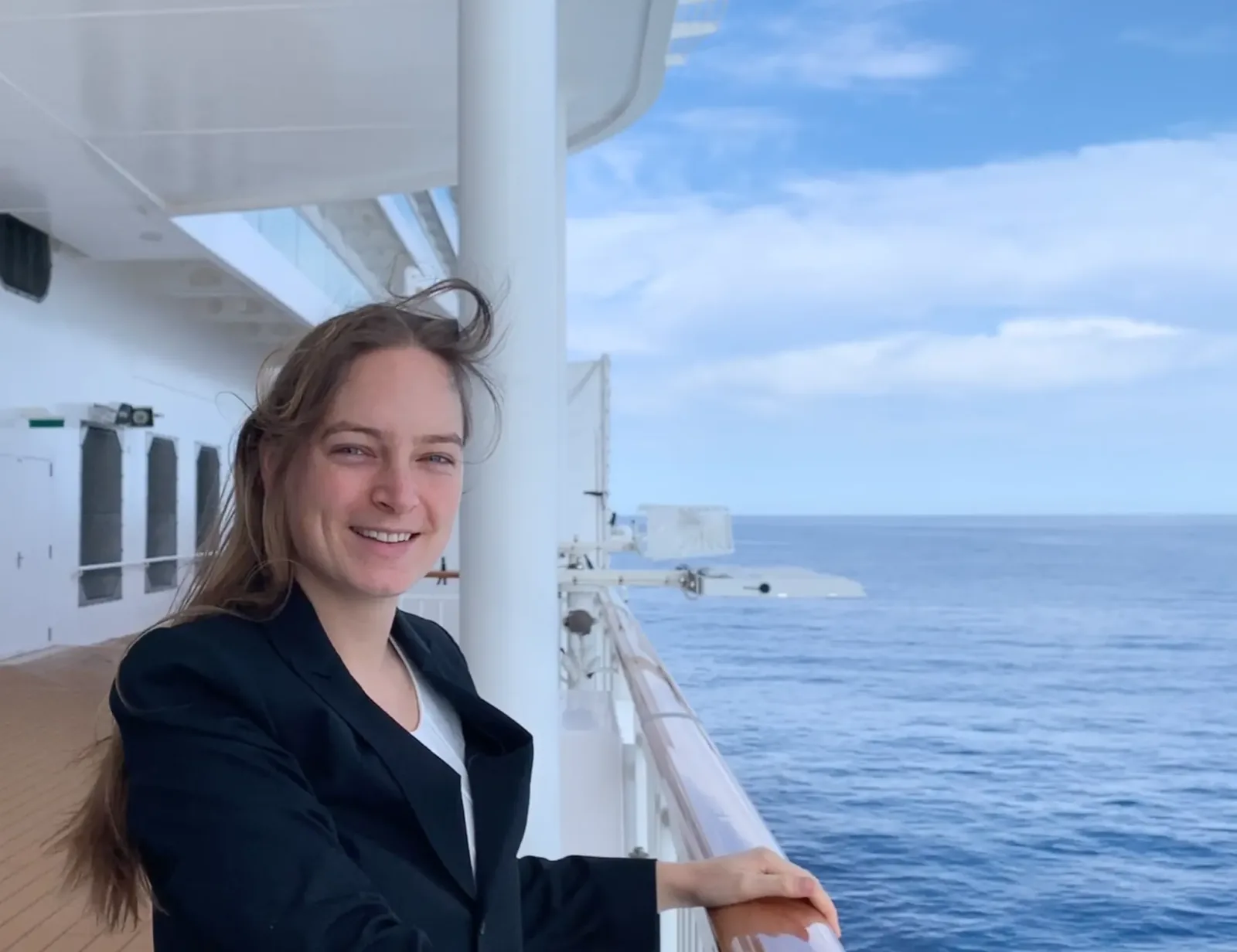 Frau lächelnd an Schiffsreling mit Meerblick, Business-Outfit, Portrait