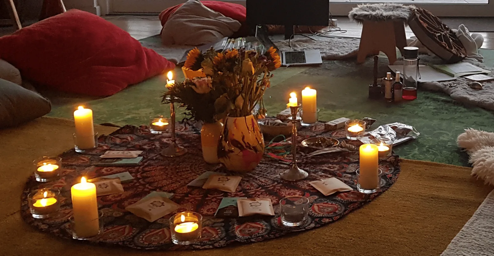 Altar-Setup mit getrockneten Sonnenblumen, brennenden Kerzen und Tarotkarten auf gemustertem Tuch
