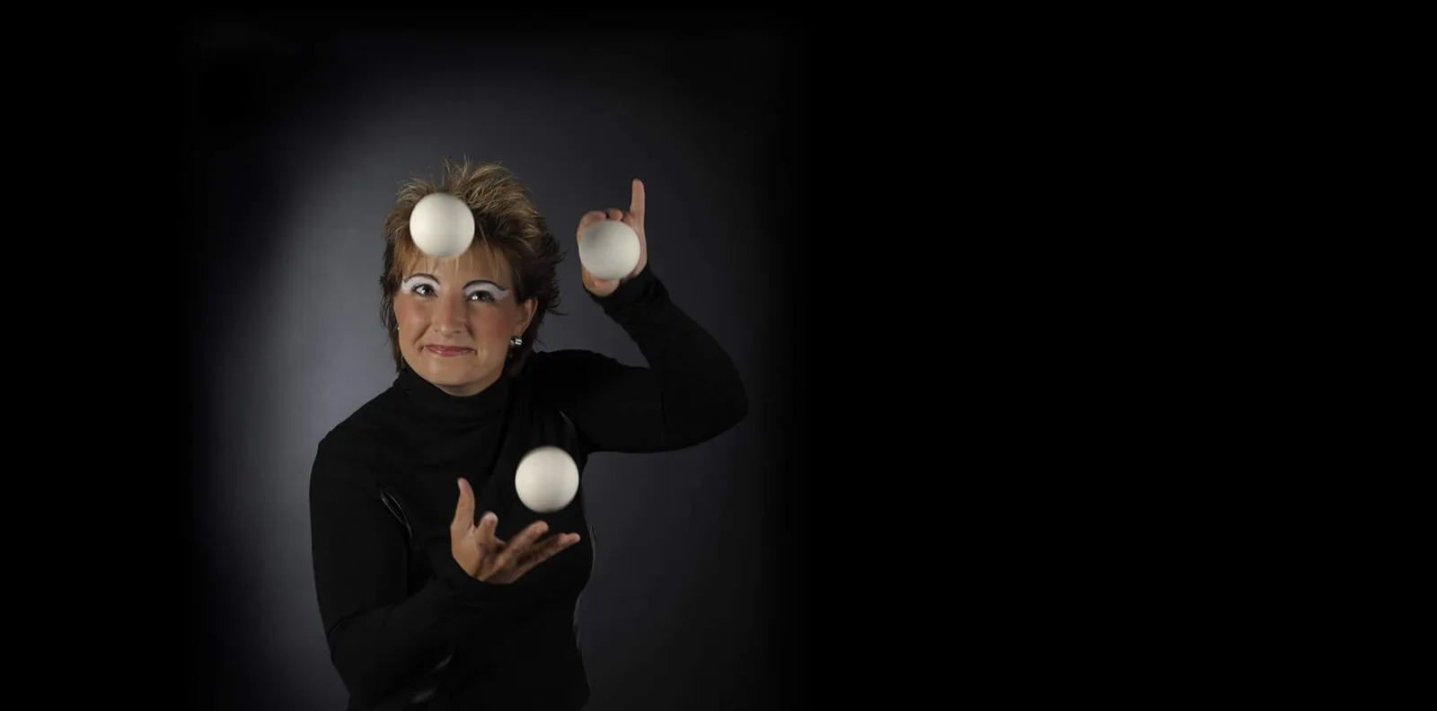 Julia Schmitz jongliert weiße Bälle, schwarzer Hintergrund, Porträt