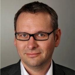 Porträtfoto eines Mannes mit Brille in Geschäftskleidung
