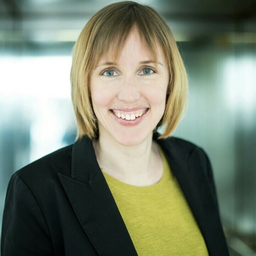 Porträtfoto einer Frau mit blonden Haaren und gelbem Top in schwarz-weißer Jacke