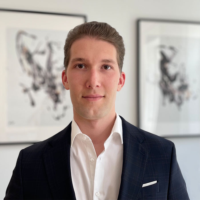 Porträt Mann in dunklem Anzug und weißem Hemd vor modernem Büro-Interior mit Kunstwerken