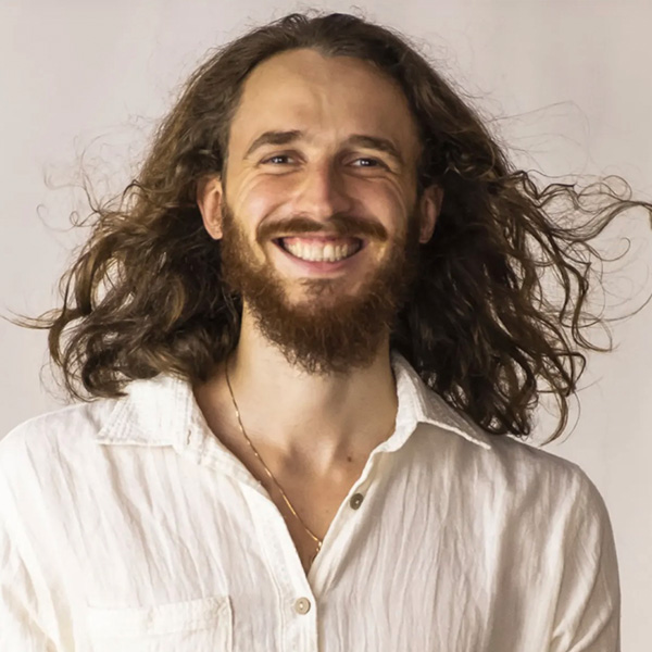Portrait des Sprechers Daniel Alan mit langen braunen Haaren und weißem Hemd
