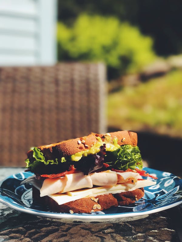 Sandwich mit Salat und Käse auf blauem Teller im Garten
