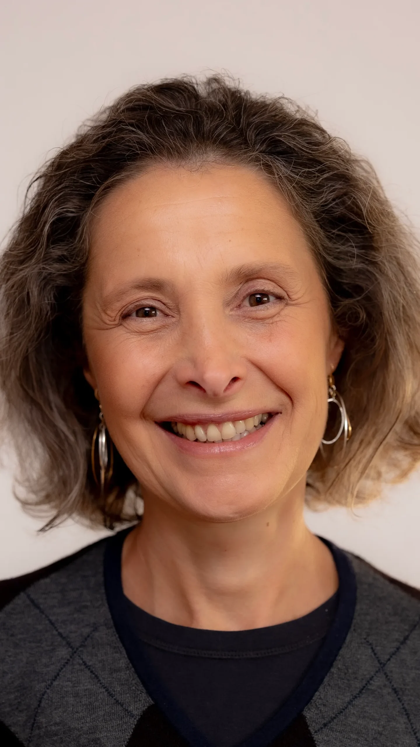 Kopfportrait einer Frau mit schulterlangen braunen Haaren, schwarzem Shirt, vor hellem Hintergrund