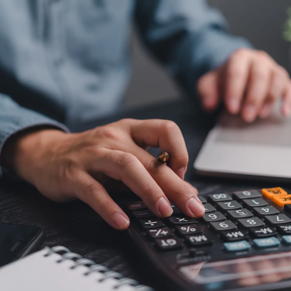 Hand mit Ring über Taschenrechner und Notizbuch, Geschäftsanalyse und Finanzplanung