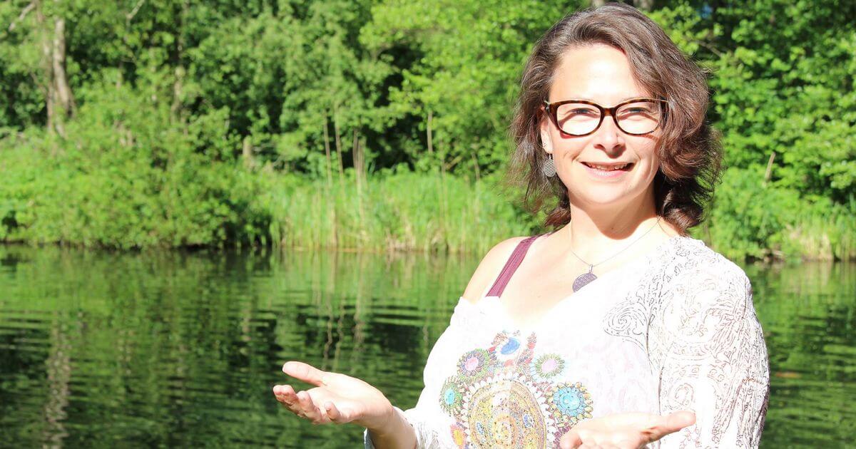 Porträt von Heike Wagner lächelnd am See mit grünem Walduntergrund, Autorin und Kursanbieterin