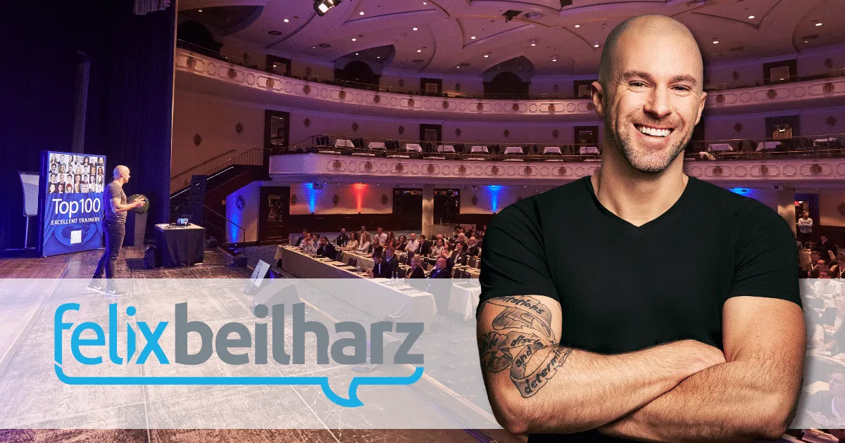 Felix Beilharz auf einer Bühne bei einer Veranstaltung, im Hintergrund ein Auditorium, Branding im Vordergrund