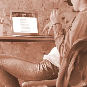 Mockup einer Person am Laptop, die auf den Bildschirm schaut; zeigt die Online-Kursplattform von Der Kompass