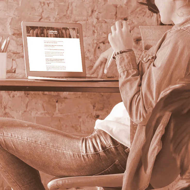 Mockup einer Person am Laptop, die auf den Bildschirm schaut; zeigt die Online-Kursplattform von Der Kompass
