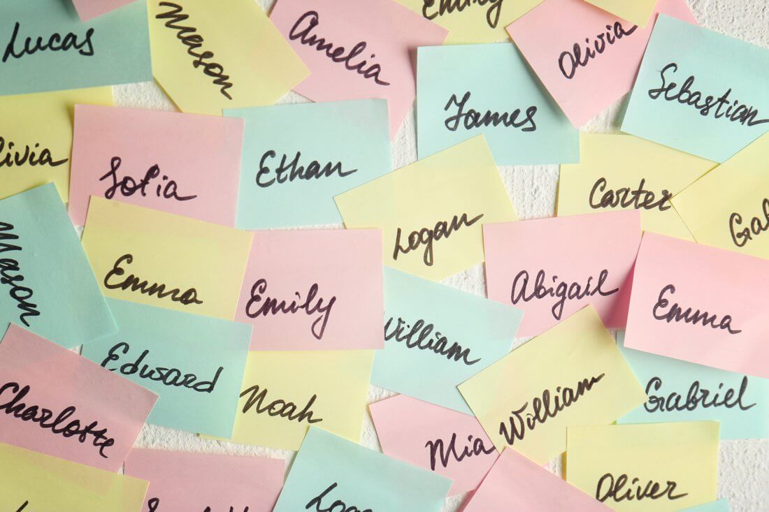 Bunte Notizzettel mit handgeschriebenen Kindernamen auf weißem Untergrund