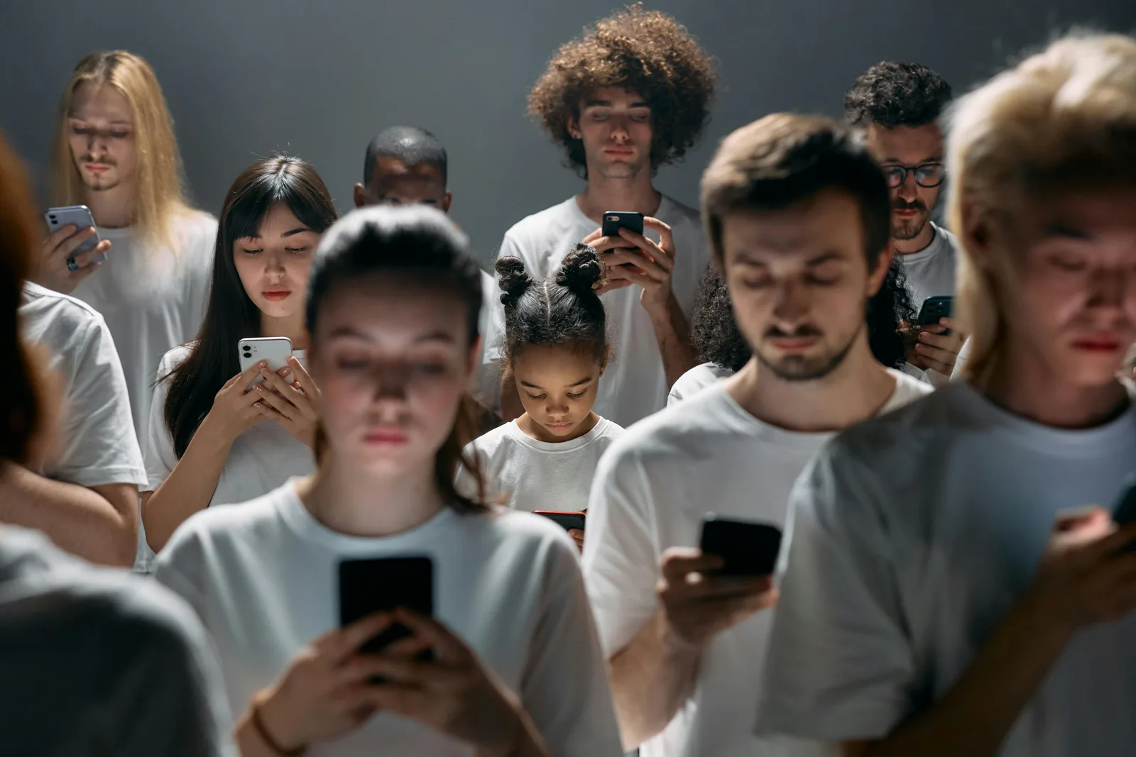 Gruppe von Menschen in weißen T-Shirts mit Smartphones, fokussiert auf ihre Geräte