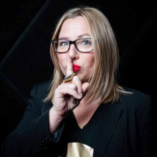 Porträt Angelika Buchmayer, Frau mit blondem Haar, Ohrringe, schwarzem ärmellosen Top, lächelnd