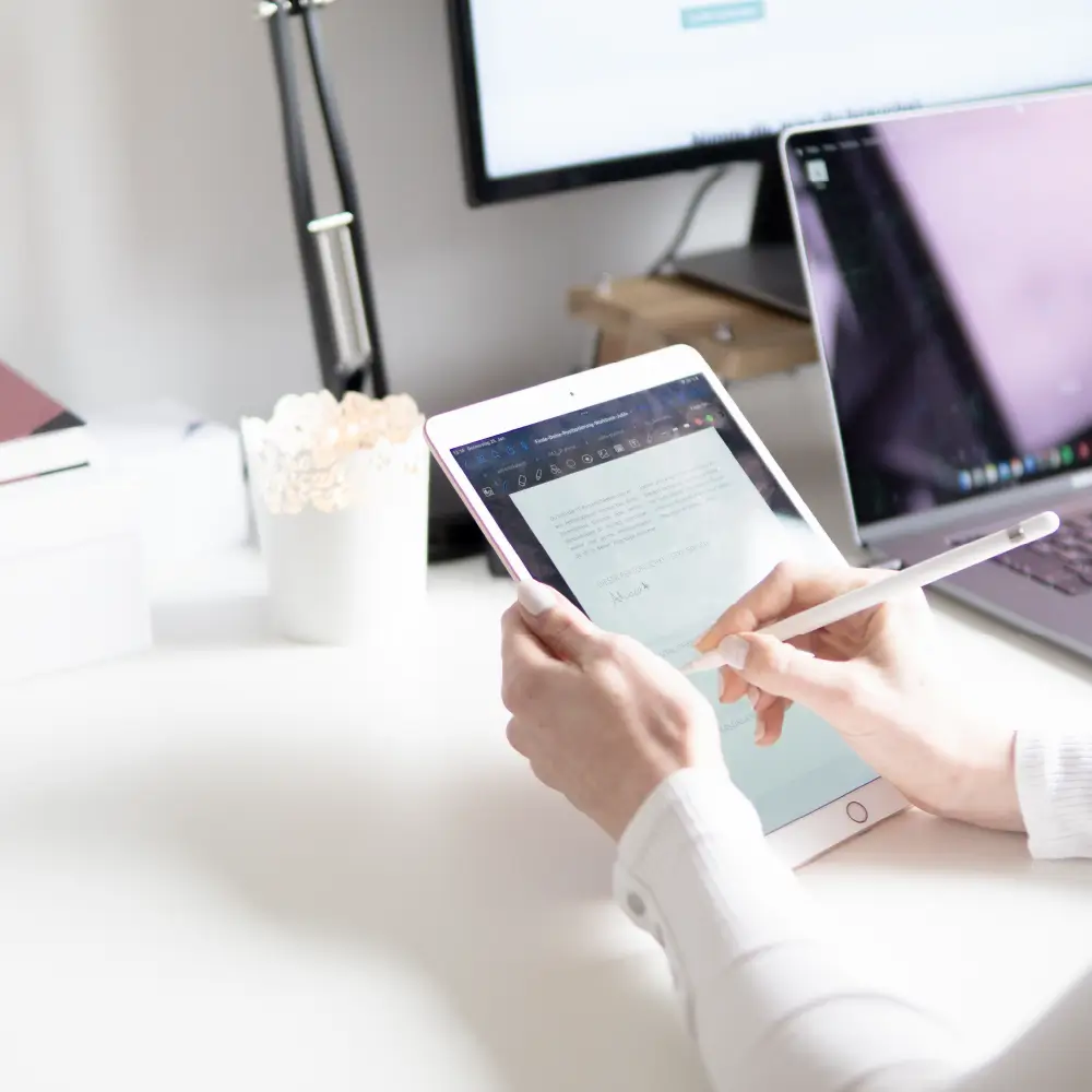 Tablet mit Positionierungs-Workbook auf Schreibtisch, Hände bedienen Gerät