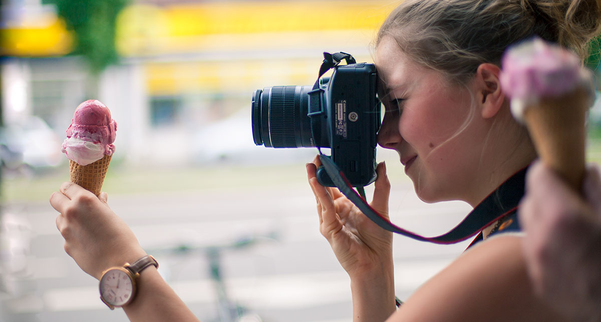 Junges Mädchen fotografiert Eistüte mit Spiegelreflexkamera