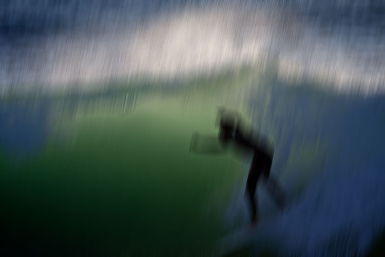 Regennasser Surfer im Meer mit Motion-Blur-Effekt