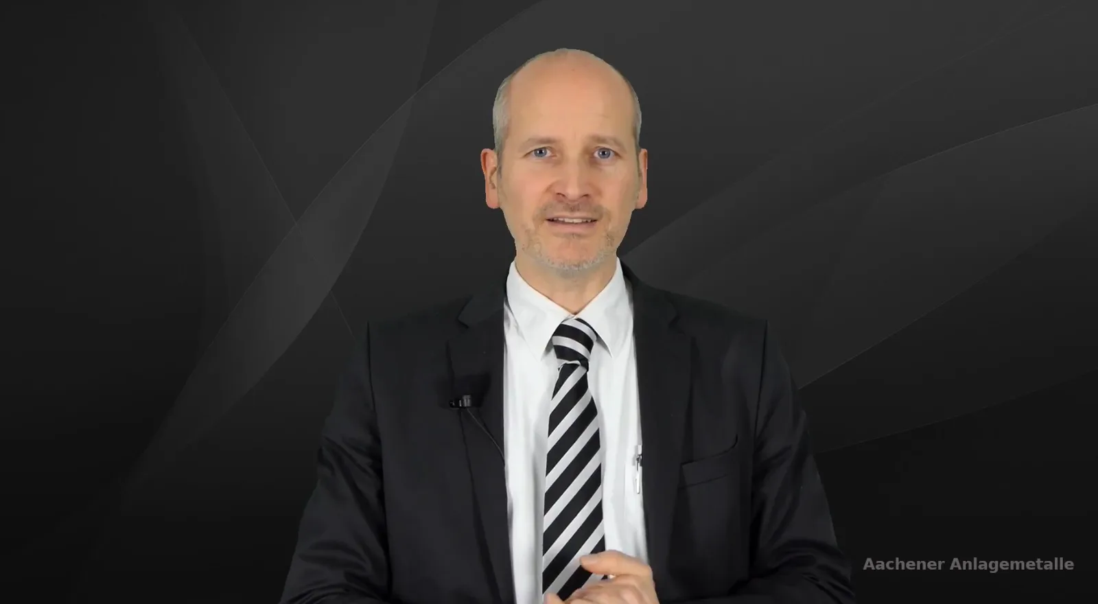 Martin Weinberg von Aachener Anlagemetalle im Business-Anzug mit gestreifter Krawatte vor dunklem Hintergrund
