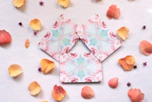 Envelope mit Rosen-Muster umgeben von gelben und orange Blütenblättern