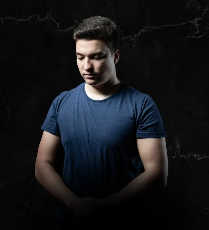 Porträt eines jungen Mannes mit dunklem Haar vor schwarzem Hintergrund mit nachdenklichem Blick nach unten