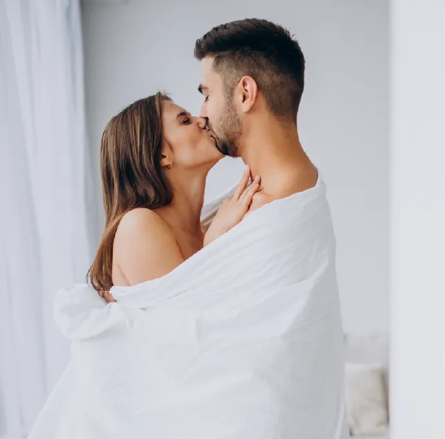 Paar küsst sich zärtlich in heller Umgebung mit weißem Tuch, halbnahe Aufnahme mit Fokus auf Gesichter und Nähe