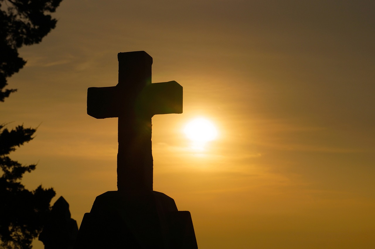 Silhouette eines Kreuzes gegen goldenen Sonnenaufgang