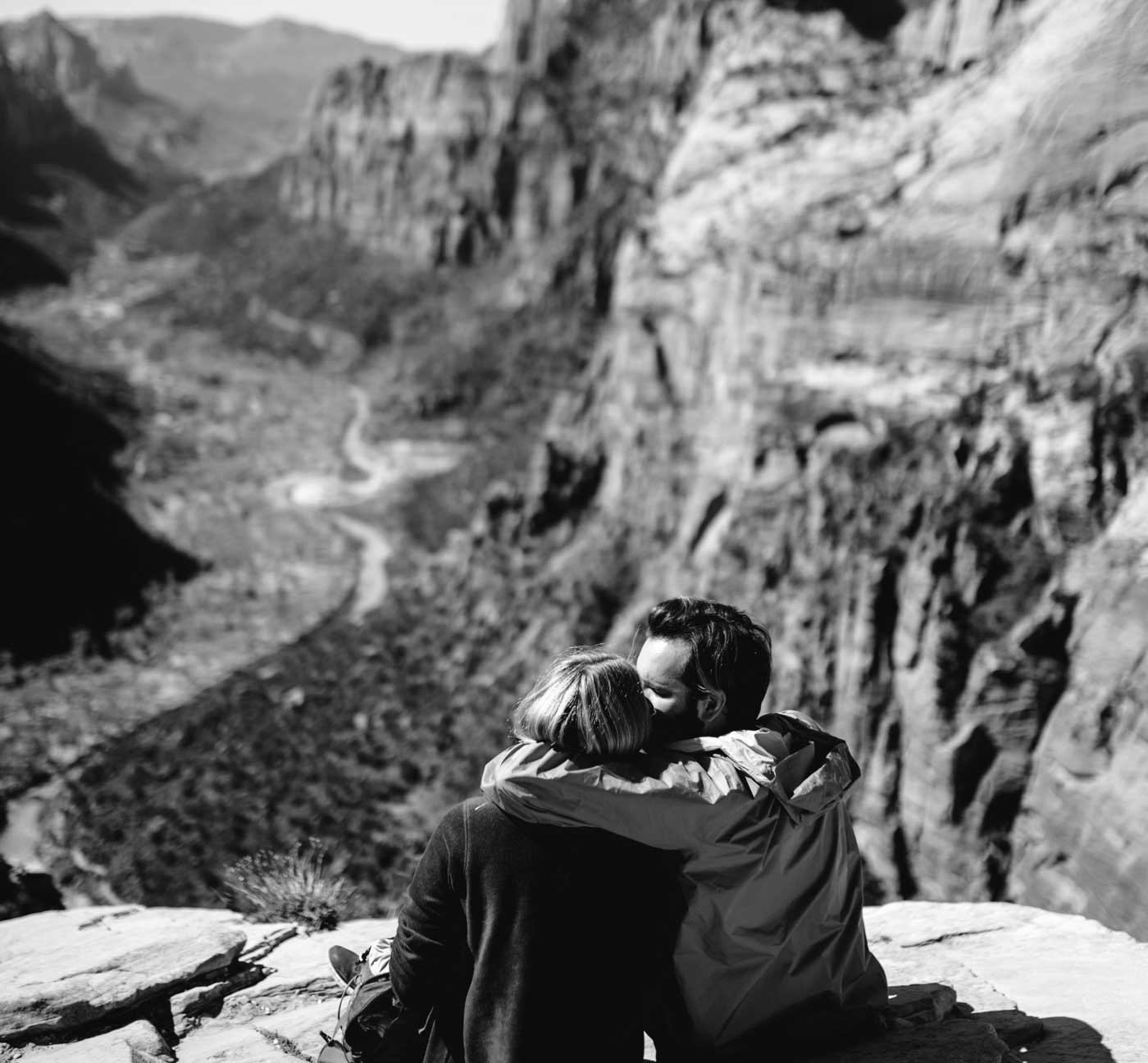 Schwarz-Weiß-Fotografie eines Paares von hinten in einer Bergschlucht, Stein- und Felsformationen im Hintergrund