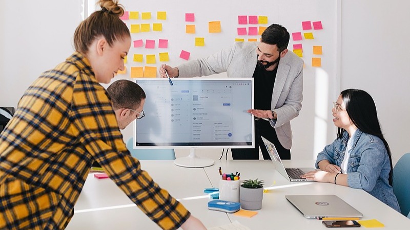 Diverse Team bei Brainstorming-Workshop mit Sticky Notes und Monitor-Display