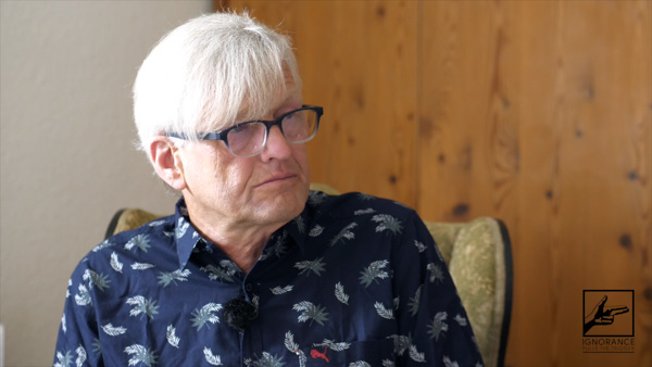Hermann Ploppa, Politologe, Portrait mit Brille und Holzwand-Hintergrund