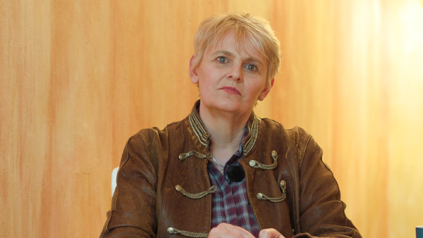 Porträt Bilbo Calvez vor gelblich-orangem Wandhintergrund, blonde Haare