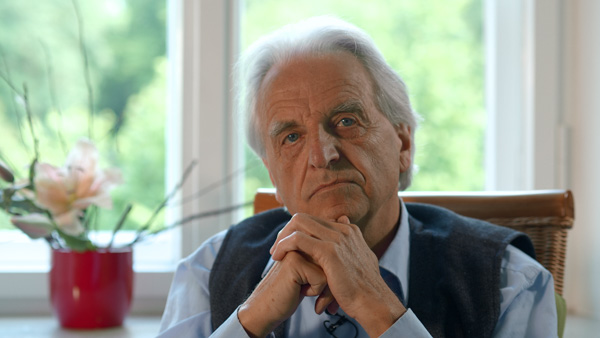 Porträt Clemens Kuby auf Wiese mit Gräsern, weißes T-Shirt, Mikrofon