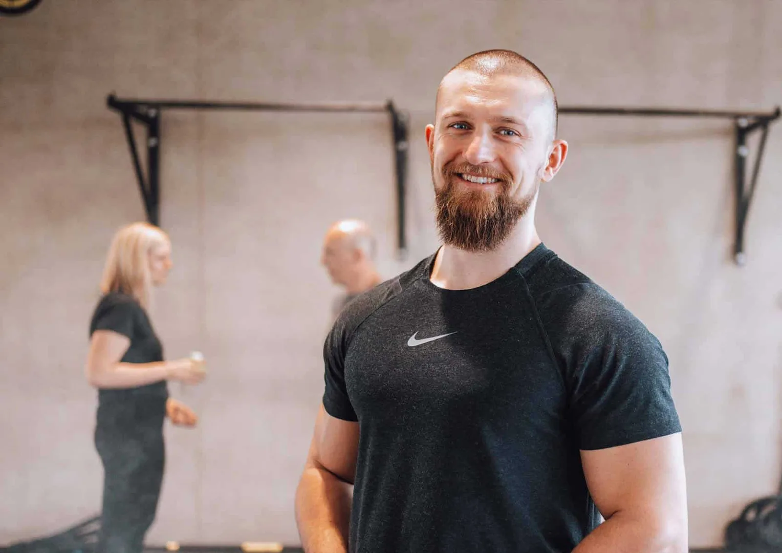 David Bachmeier lächelt in die Kamera, trägt schwarzes Nike-Shirt, im Hintergrund verschwommene Trainingsumgebung
