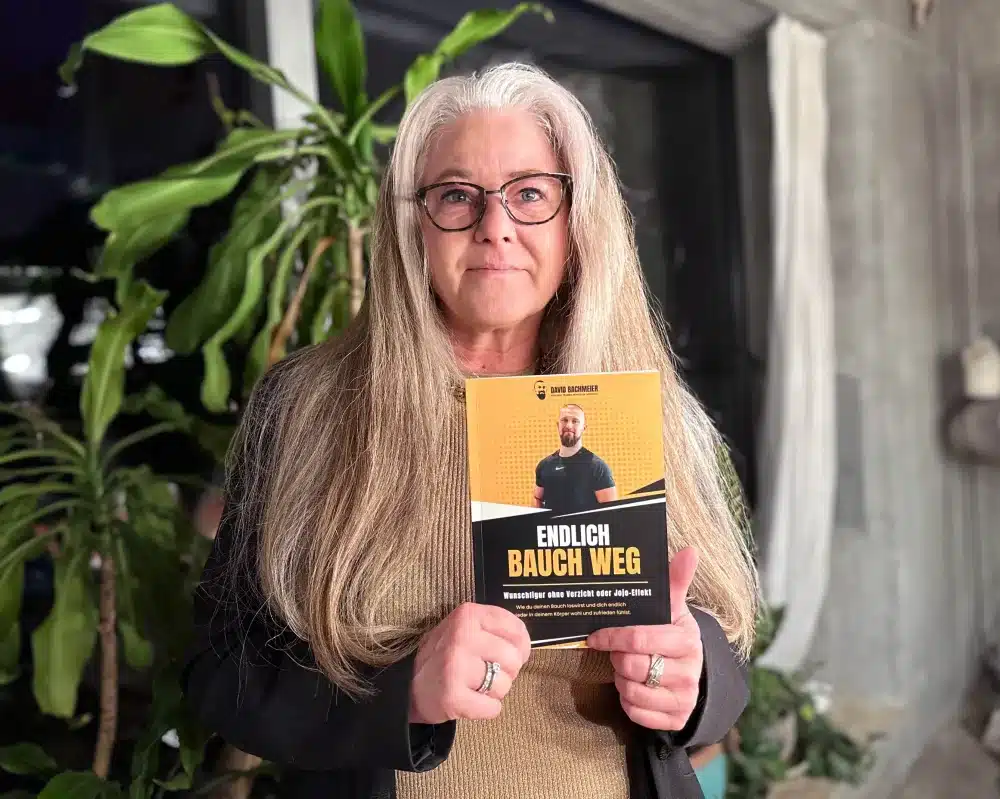 Testimonial-Foto einer Frau mit langen grauen Haaren und Brille, hält das Buch vor sich