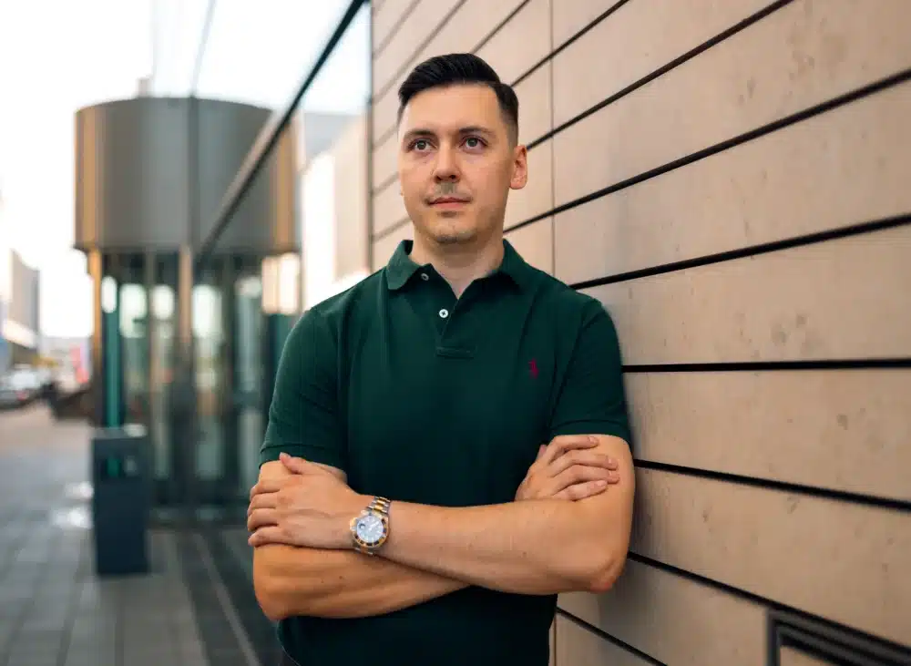 Porträt eines jungen Mannes in grünem Poloshirt vor moderner Architektur