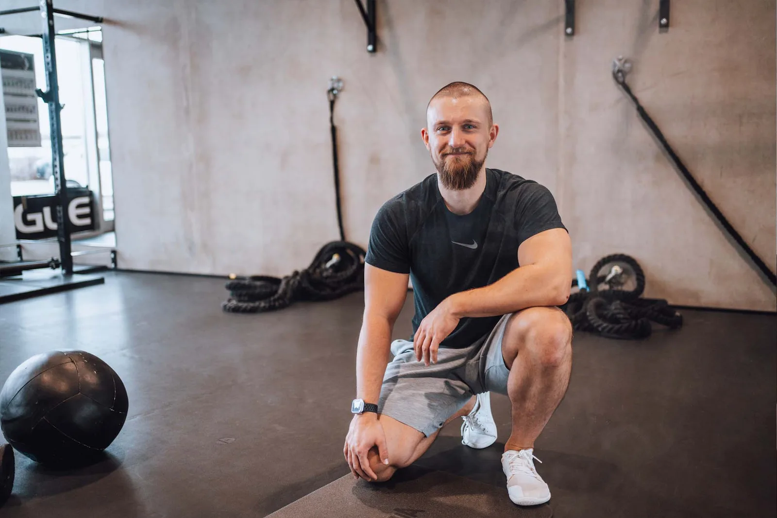 David Bachmeier sitzt auf Trainingsball im Fitnessstudio, umgeben von Trainingsgeräten, motivierendes Porträt