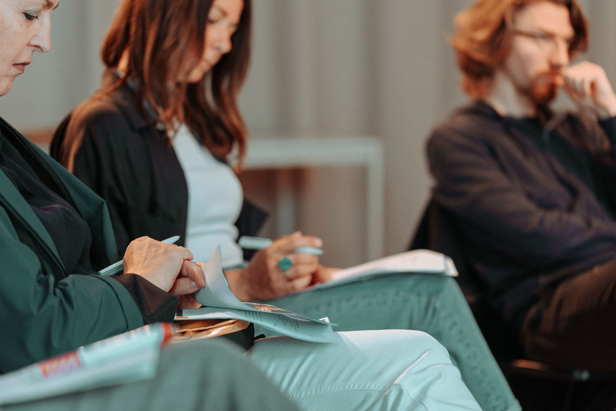 Gruppe von Frauen mit rötlichen Haaren in Geschäftskleidung sitzt zusammen und diskutiert über Unterlagen