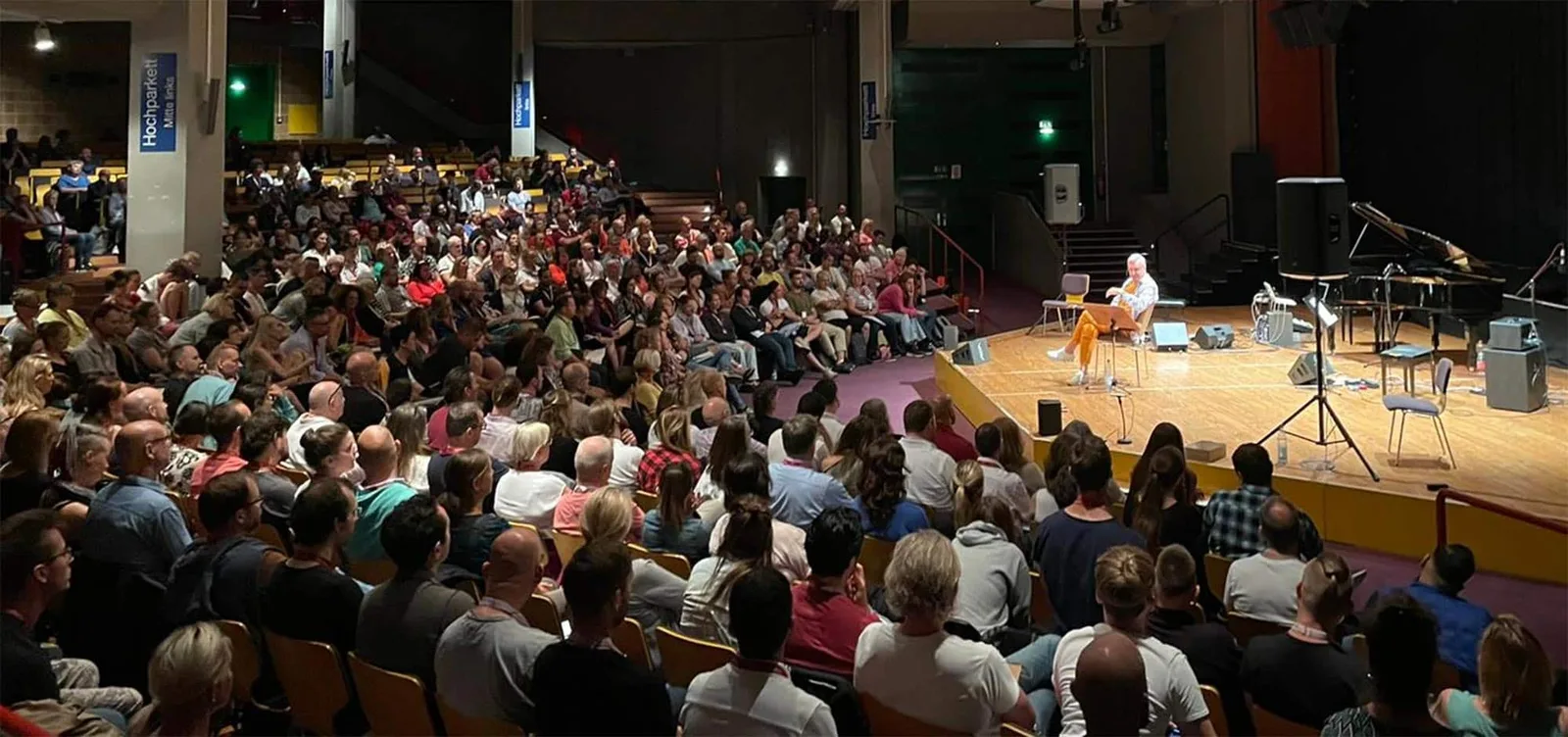 NLP Practitioner 2023 Seminar: Großer Saal mit hunderten Teilnehmern und Trainer auf Bühne