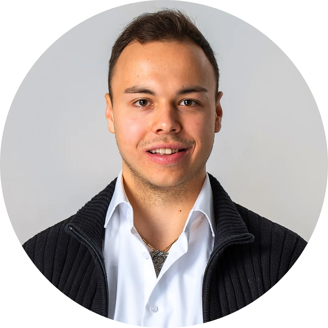Robin Hofmann Profilbild - junger Mann mit dunklem Haar, weißem Hemd und schwarzer Jacke vor grauem Hintergrund
