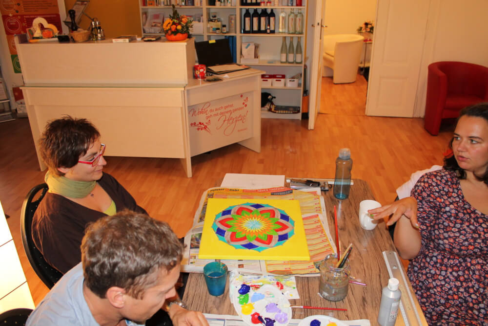 Energiebilder selber malen – Online Videomalkurs Mandala 20 Kurs-Workshop mit Teilnehmern an Tischen mit Mandala-Malwerken