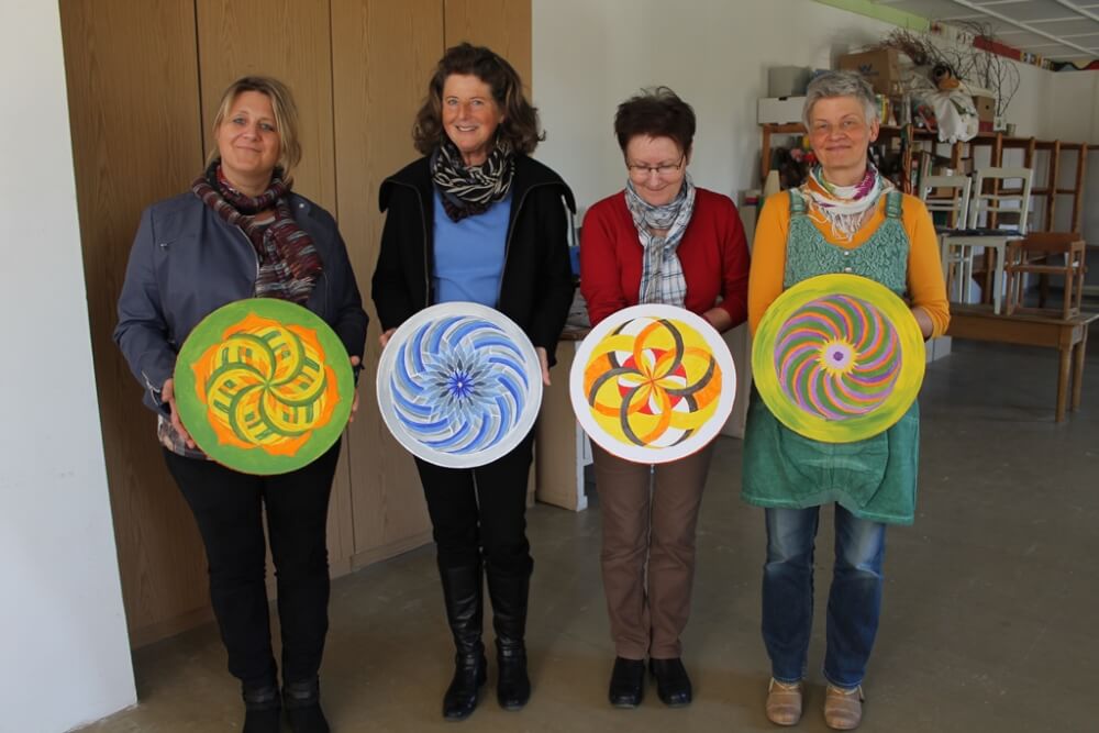 Energiebilder selber malen – Online Videomalkurs Mandala 21 Vier Frauen halten ihre fertigen bunten Mandala-Kunstwerke stolz vor sich