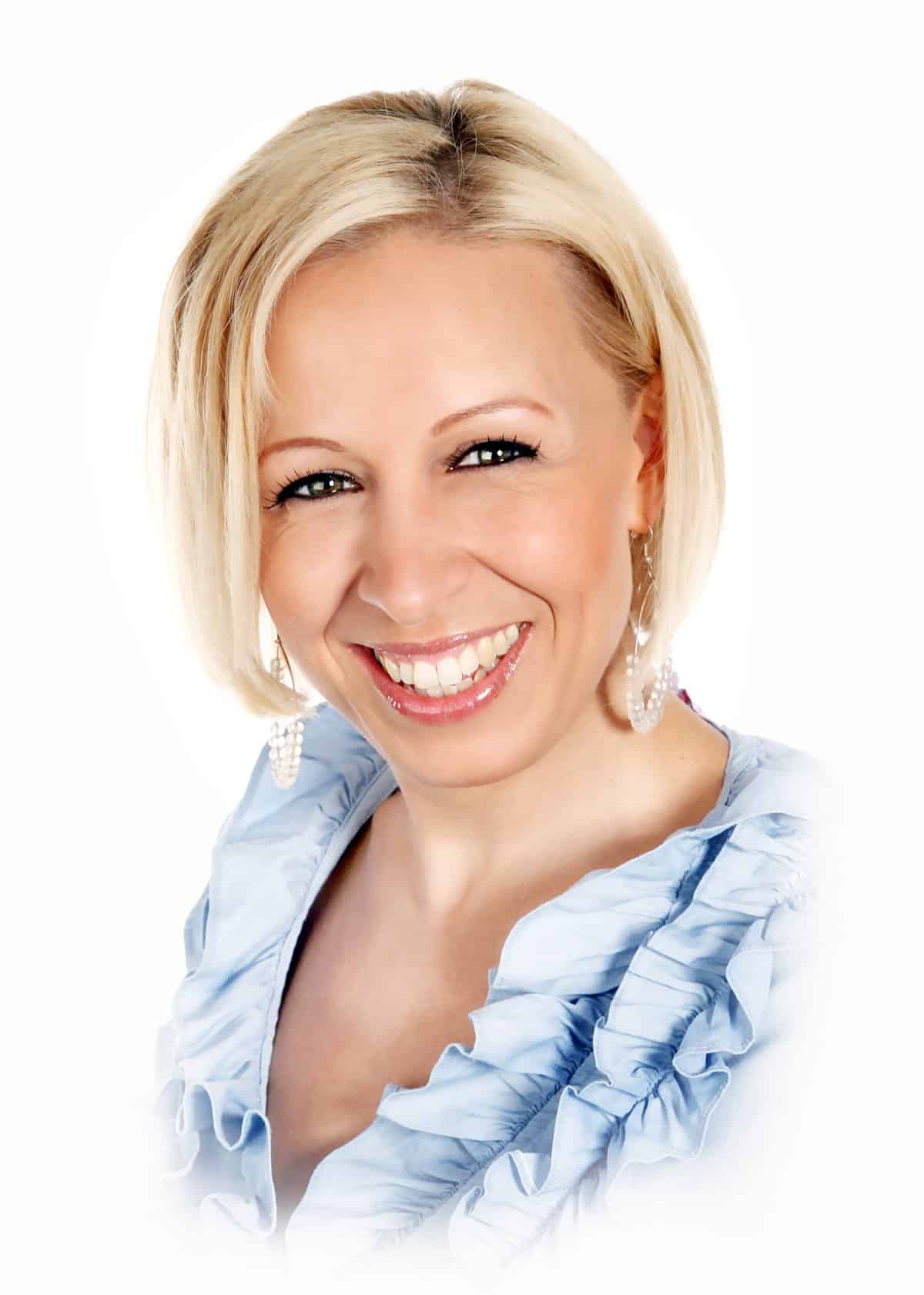 Porträtfoto Katja Amberg, blonde Frau mit hellblauem Oberteil lächelnd vor weißem Hintergrund