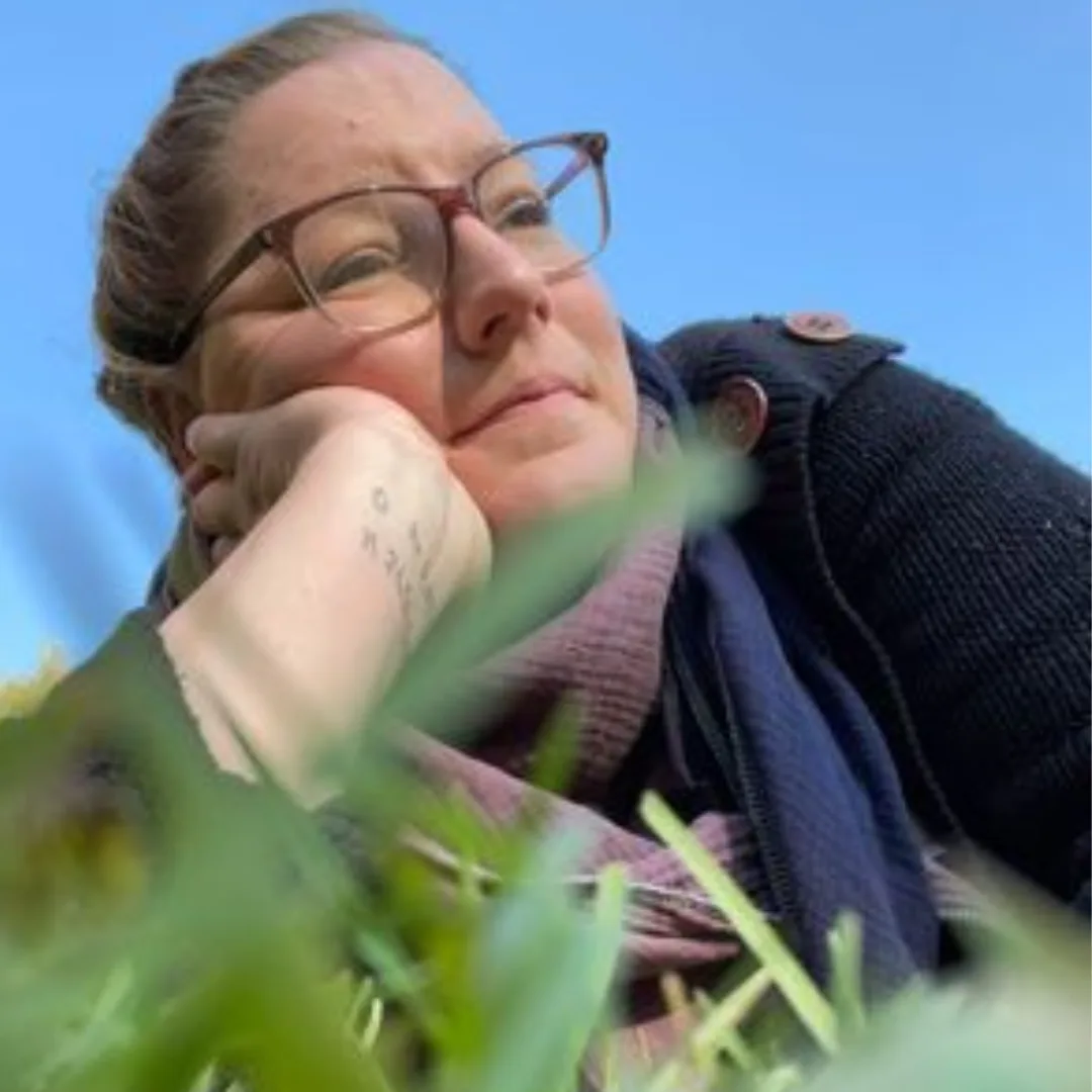 Porträt Denise Pecha mit Brille auf grünem Naturhintergrund