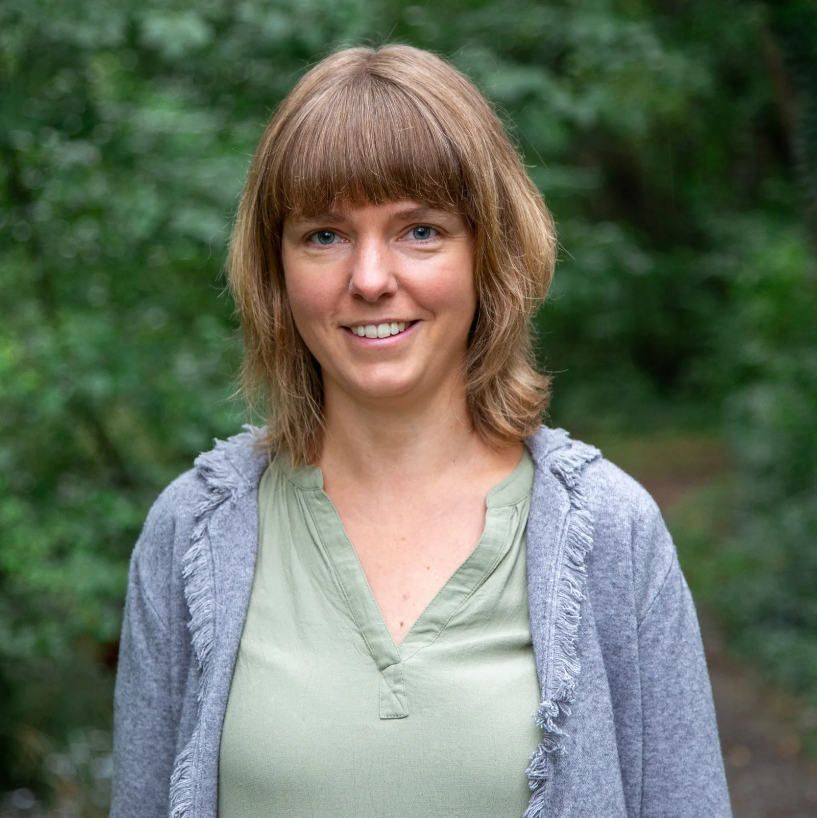 Porträt von Jenny Zuber mit braunem Haar vor grünem Naturhintergrund